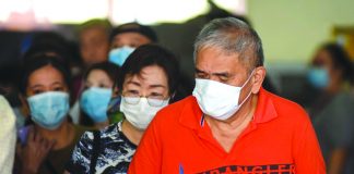 Commuters wearing face masks pass through a turnstile at the LRT Line 1 Baclaran station, Manila on Feb. 12. ABS-CBN