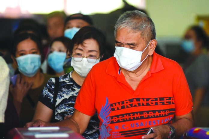 Commuters wearing face masks pass through a turnstile at the LRT Line 1 Baclaran station, Manila on Feb. 12. ABS-CBN