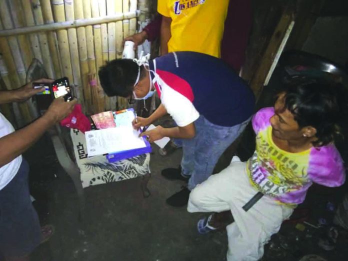 Darwin Tabotabo An antidrug officer inspects items seized from Darwin Tabotabo during an entrapment operation in Barangay 19, Bacolod City on Feb. 3. POLICE STATION 9/BCPO