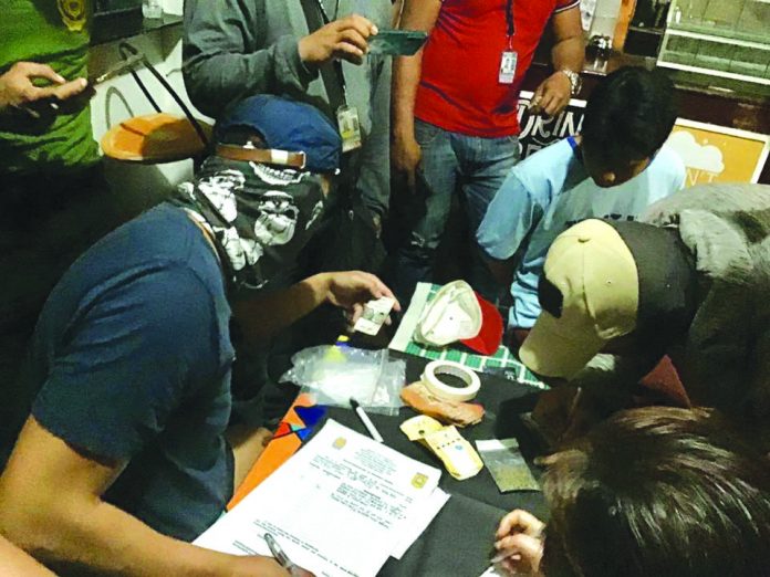 Antidrug officers inspect items seized from Jerenz Abuel. He was nabbed in an entrapment operation in Barangay Poblacion, Kalibo Aklan on Feb. 18. BOY RYAN ZABAL/PN