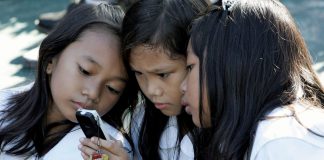 Students using a cell phone for text messaging, Quezon City, Philippines. Bullit Marquez/AP