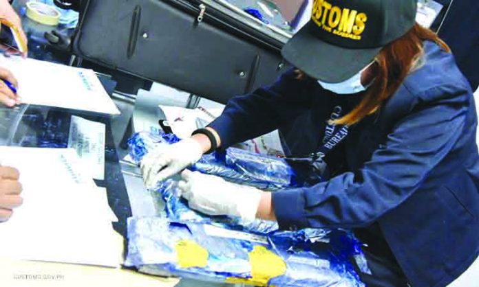 An antidrug operative inspect the suspected illegal drugs seized from a suspected Thai drug mule at the Ninoy Aquino International Airport on Feb. 3. CUSTOMS.GOV.PH