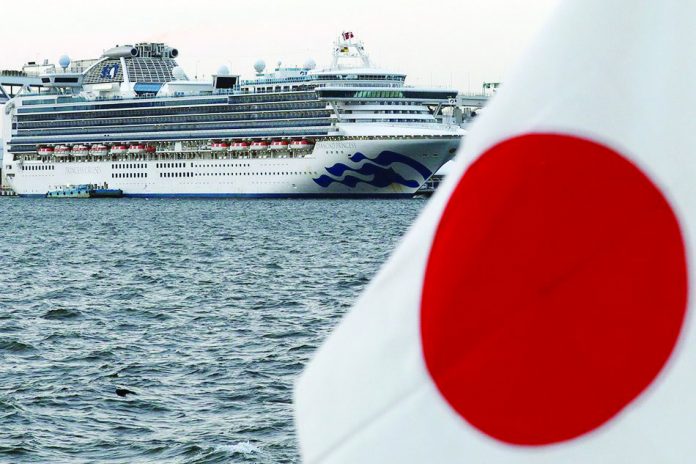 The cruise ship Diamond Princess is pictured beside a Japanese flag as it lies at anchor while workers and officers prepare to transfer passengers who tested positive for coronavirus, at Daikoku Pier Cruise Terminal in Yokohama, south of Tokyo, Japan on Feb. 12, 2020. REUTERS