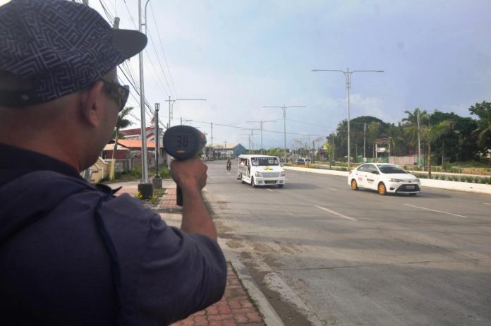 SPEED CHECK. A traffic enforcer checks the speed of these vehicles on Sen. Benigno Aquino Jr. Avenue, a traffic discipline zone in Mandurriao, Iloilo City. Drivers’ lack of discipline contributes to traffic congestion and causes vehicular accidents. PN PHOTO