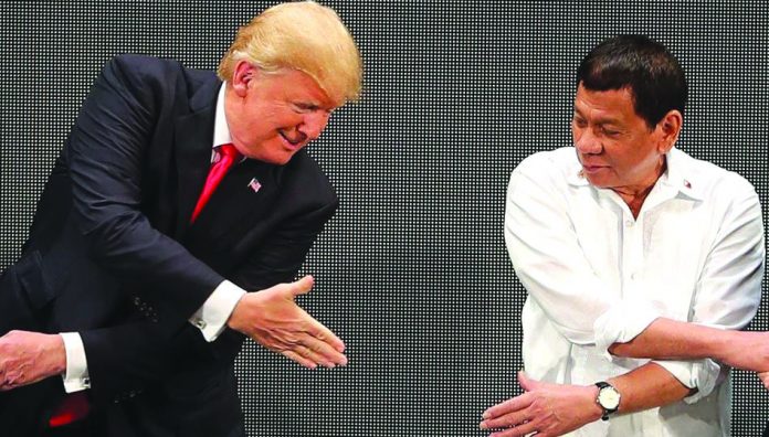 United States President Trump and President Rodrigo Duterte attempt to shake hands in this November, 2019 photo. Trump dismissed concerns about the Philippines canceling a major military accord, saying the decision would save Americans money. GETTY IMAGES