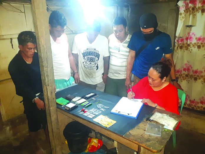 An antidrug officer inspects items seized from John Rey Tayucon, Dexter Dagatan, Elesaldie Cadalman and Mark Bille. The suspects were arrested in an entrapment operation in Barangay Villamonte, Bacolod City on Feb. 7. POLICE STATION 2/ BCPO