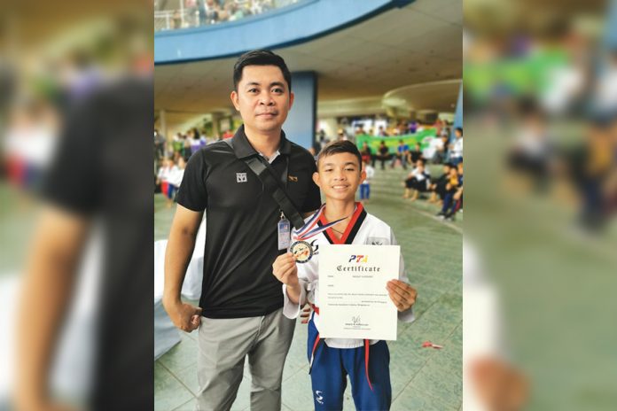 Head coach Mark Pinggol poses with male cadet black belt poomsae winner Cyd Edryc Esmaña. MARK PINGGOL