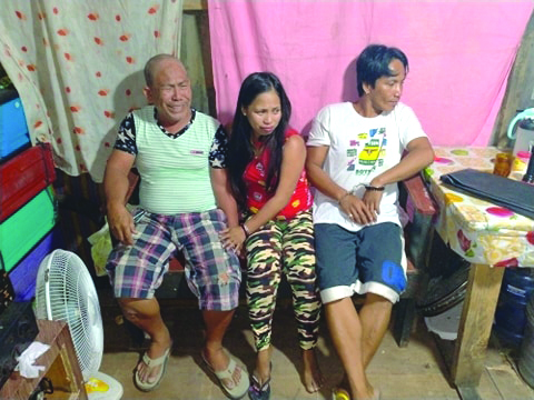 Drug suspects Armando Galgarin, Raquel Galgarin and Arlie Galgarin sit down while antidrug personnel inspect items seized from them during an entrapment operation in Barangay Banago, Bacolod City on March 12. POLICE STATION 2