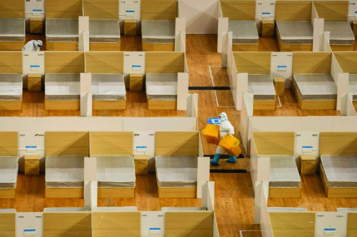 Makeshift hospitals A staff member removes waste after the final patients were discharged from a temporary hospital set up to treat people with the COVID-19 coronavirus in a sports stadium in Wuhan, China. AFP