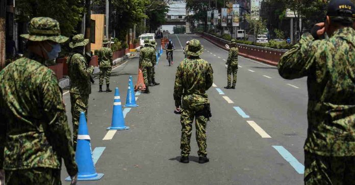 Policemen are seen at a checkpoint on the border between Quezon city and Manila on 18 March, 2020, as the Philippines imposed measures to curb the spread of COVID-19. AFP