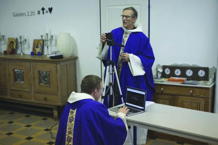 Priest Philippe Rochas, left, and Jean-Benoit de Beauchene pack up livestreaming equipment after holding a closed door Sunday mass at the St. Vincent de Paul church in Marseille, southern France, Sunday, March 22, 2020. AP