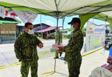 Western Visayas police director Brigadier General Rene Pamuspusan (left) gives boxes of face masks and fruits to Dumarao chief of police Larnel Frial, which are to be used by personnel who conduct checkpoint at the border of Iloilo and Capiz provinces in Barangay Aglalana, Dumarao, Capiz on March 23. PIA