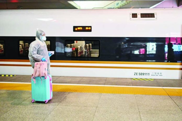 A woman wearing protective gear A woman wearing protective gear as she boards a train stopping at Wuhan, which has opened stations again to incoming passengers. AFP