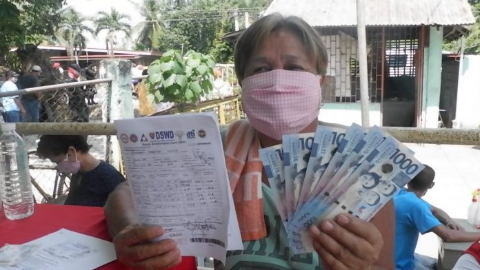 A resident of Barangay Dawis Sur, Zarraga, Iloilo receives her cash aid of P6,000 from the national government’s Social Amelioration Program