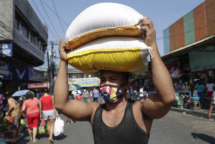 A worker carries sacks of rice A worker carries sacks of rice before market closes, after it cut its operations to lesser hours a day to curb the spread of the new coronavirus. AP