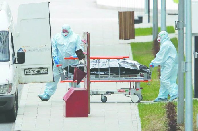 Medical specialists wearing protective gear Medical specialists wearing protective gear push a stretcher towards an ambulance while relocating a non-transparent bag outside a hospital for patients infected with the coronavirus disease on the outskirts of Moscow, Russia April 20, 2020. REUTERS