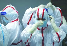 China virus epicenter raises death toll 50% Medical staff put on protective equipment before attending to COVID-19 patients at the Red Cross Hospital in Wuhan in China's central Hubei province on March 16, 2020. AFP
