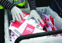 Trump, Dems clash on boosting mail-in voting during pandemic In this March 10, 2020, file photo wearing gloves, a King County Election worker collect ballots from a drop box in the Washington State primary, in Seattle. AP
