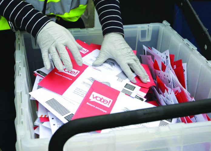 Ballots from a drop box in the Washington State primary In this March 10, 2020, file photo wearing gloves, a King County Election worker collect ballots from a drop box in the Washington State primary, in Seattle. AP