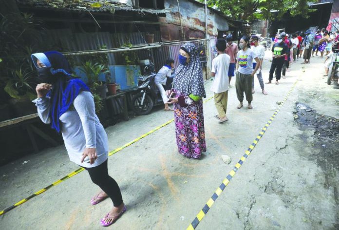 World 3 Residents practice social distancing as they queue for donated food during the coronavirus pandemic in a slum area in Jakarta, Indonesia, Wednesday, April 22, 2020. AP