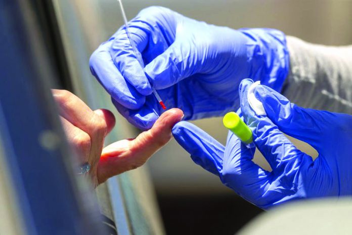 A health worker takes a blood sample for a COVID-19 antibody