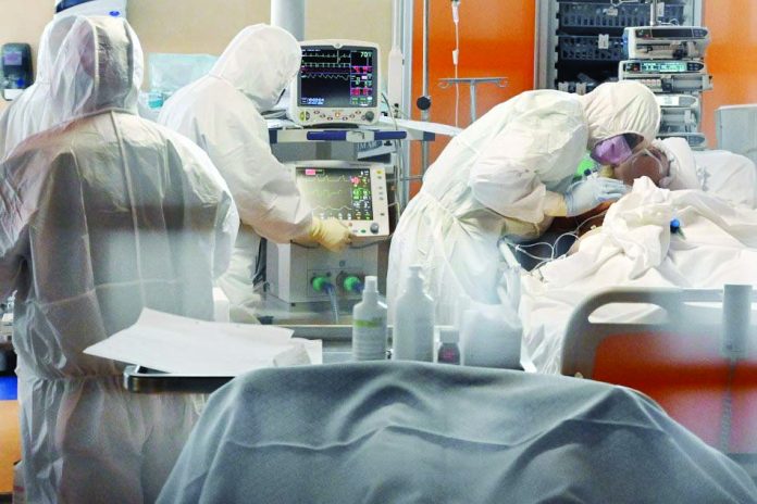 A medical worker in protective gear (right) tends to a patient at an intensive care unit for coronavirus COVID-19 cases.