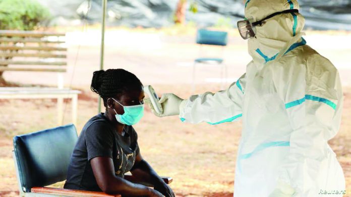A woman has her temperature checked by a healthcare worker during a nationwide lockdown to help curb the spread of the coronavirus disease (COVID-19), at a mass screening and testing centre, in Harare