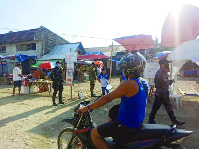 Police personnel implement social distancing and wearing of facemasks to residents at the Caticlan Public Market, Malay, Aklan on May 10.