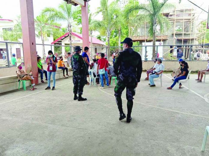 Police personnel provide security during the social amelioration program (SAP) financial aid distribution in Barangay Lanot, Roxas City, Capiz on May 3.