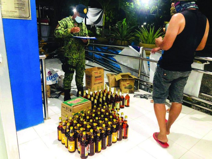 This police officer inspects liquors seized from two persons in Barangay Ilaures, Bugasong, Antique on May 21.