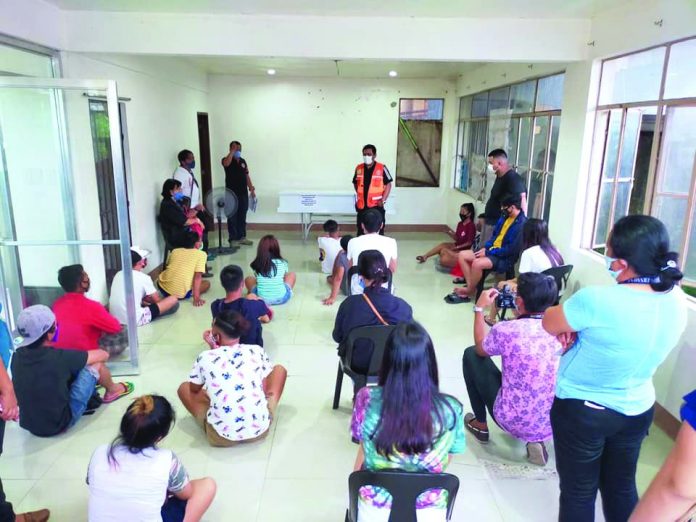 With a casket on the background, local authorities lecture different violators of the general community quarantine at the Roxas City Crisis Center on May 4.
