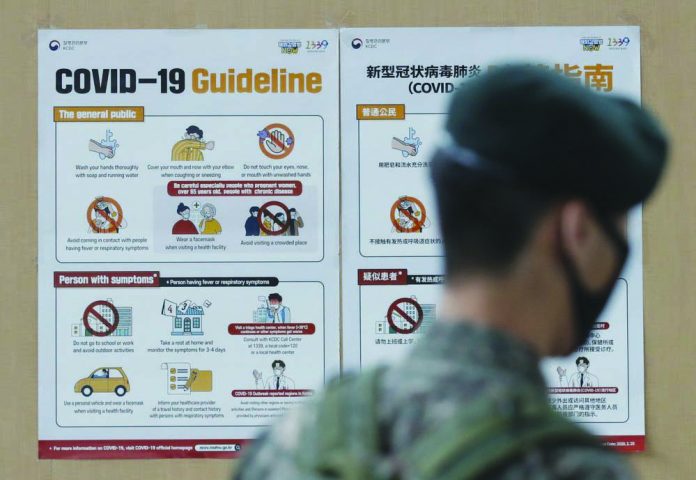 A South Korean soldier wearing a face mask walks near banners showing precautions against the new coronavirus in Seoul, South Korea, Wednesday, June 17, 2020.