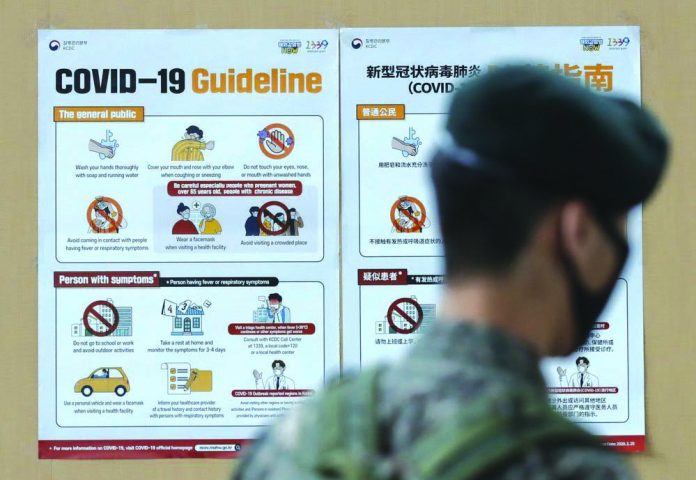 A South Korean soldier wearing a face mask walks near banners showing precautions against the new coronavirus in Seoul, South Korea, Wednesday, June 17, 2020.