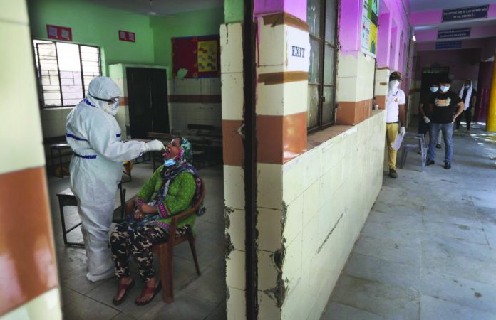 A health worker takes a swab sample of a woman for the COVID-19 rapid antigen test as other waits , in New Delhi, India, Wednesday, June 24, 2020.