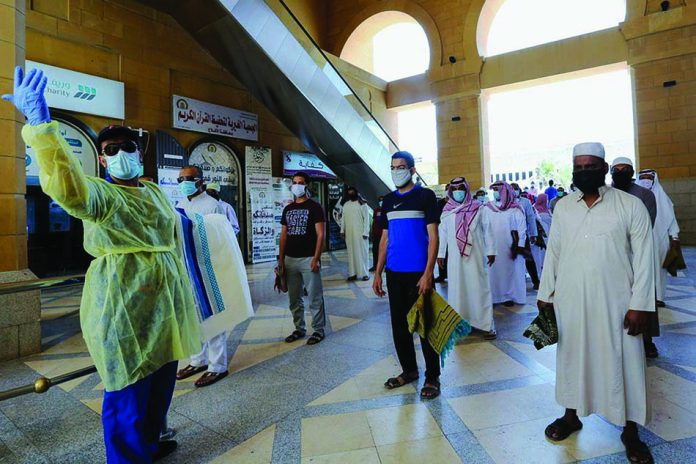 A security man checks the worshipers before they perform the Friday prayers inside the Al-Rajhi Mosque while practicing social distancing