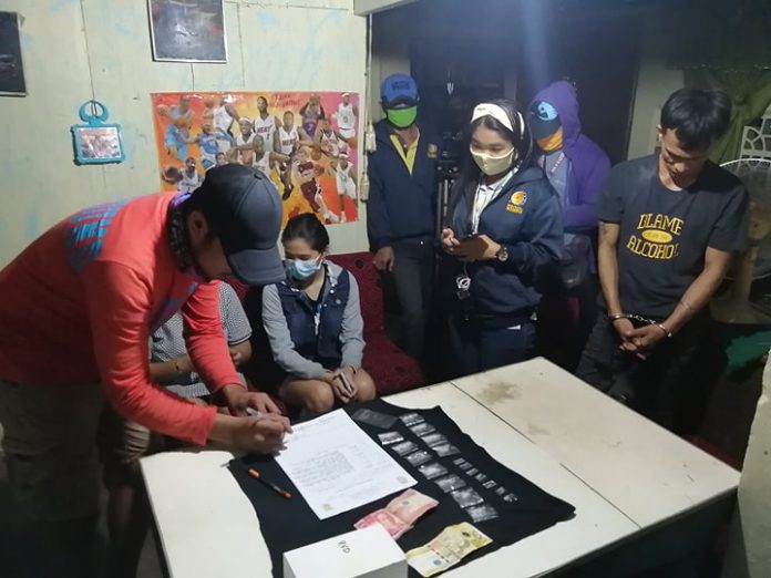 An antidrug officer inspects items seized from Reynaldo Villaespin, who was nabbed in an entrapment operation in Barangay Taculing, Bacolod City on June 13.