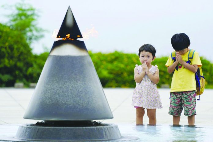 Children pray in front of the Peace of Fire at the Peace Memorial Park in Itoman, Okinawa, Japan, Tuesday, June 23, 2020.
