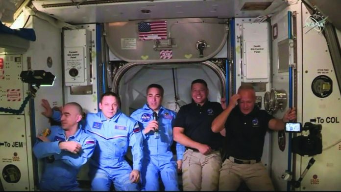 Douglas Hurley (R) and Robert Behnken (2ndR) arrive at the International Space Station, to be greeted by other astronauts