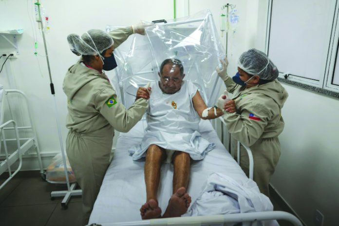Health workers assist a COVID-19 patient at the Gilberto Novaes Municipal Hospital in Manaus, Brazil