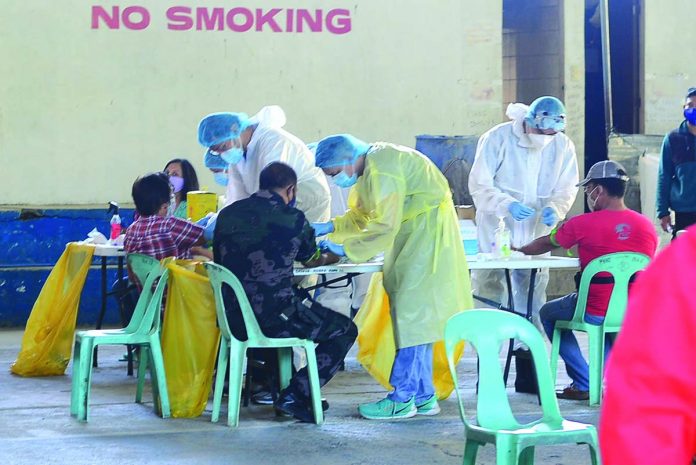 Personnel of the Iloilo City Health Office conduct blood sample rapid testing procedure to police officers at the Mandurriao Gym on Wednesday.