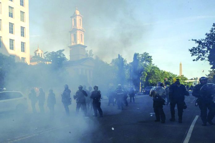 Tear gas floats in the air as a line of police move demonstrators away from St. John's Church across Lafayette Park from the White House