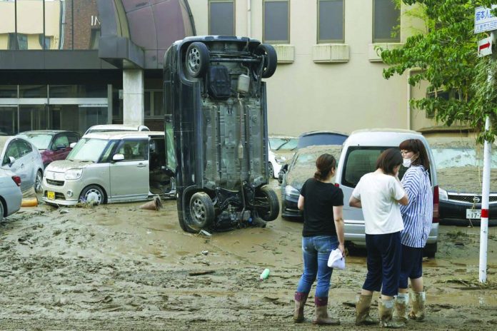 A car stands vertically on a muddy road after being washed away by flood, in Hitoyoshi, Kumamoto prefecture, southwestern Japan, Sunday, July 5, 2020.