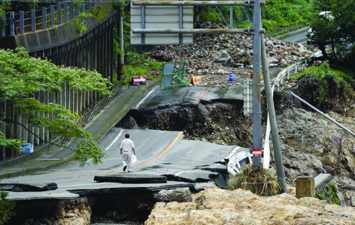A man walks on heavily damaged road following a heavy rain in Kumamura, Kumamoto prefecture, southern Japan Monday, July 6, 2020.