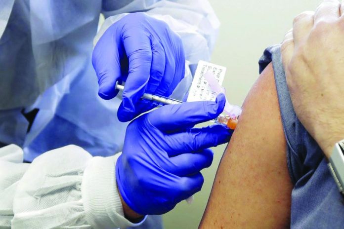 In this March 16, 2020 file photo, a subject receives a shot in the first-stage safety study clinical trial of a potential vaccine by Moderna for COVID-19, at the Kaiser Permanente Washington Health Research Institute in Seattle. AP