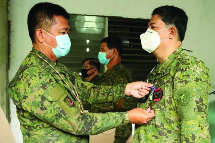 Colonel Inocencio Pasaporte, commander of the 303rd Infantry Brigade, pins the Military Commendation Medal on an Army reservist