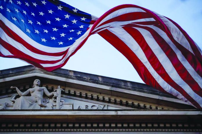 In this March 22, 2019 file photo, an American flag flies outside the Department of Justice in Washington In this March 22, 2019 file photo, an American flag flies outside the Department of Justice in Washington. The Justice Department has accused two Chinese hackers of stealing hundreds of millions of dollars of trade secrets from companies across the world and more recently targeting firms developing a vaccine for the coronavirus. AP