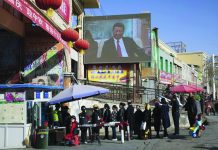 US sanctions Chinese companies over Muslim abuse complaints In this Nov. 3, 2017, file photo, residents line up at a security checkpoint into the Hotan Bazaar where a screen shows Chinese President Xi Jinping in Hotan in western China's Xinjiang region. AP PHOTO/NG HAN GUAN