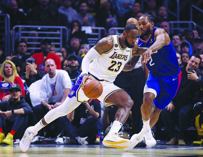 Los Angles (LA) Lakers’ LeBron James tries to evade the defense of LA Clippers’ Kawhi Leonard during a National Basketball Association match. The showdown of the two teams will air on a Philippine television network at 9 a.m. today. YAHOO! SPORTS