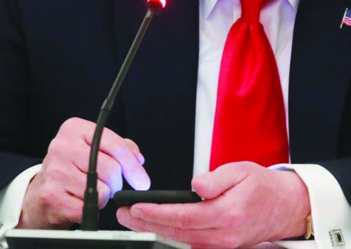 Trump United States President Donald Trump taps the screen on a mobile phone at the approximate time a tweet was released from his Twitter account, during a roundtable discussion at the White House in Washington on June 18, 2020. REUTERS/LEAH MILLIS/FILE PHOTO