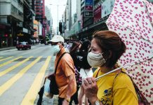 HK implements tough coronavirus restrictions Pedestrians prepare to walk across a main road in Hong Kong on July 20, 2020. AFP